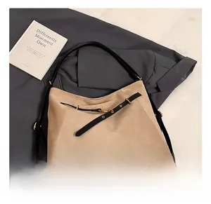 Detail of khaki frosted suede tote bag with black leather straps on a grey coat