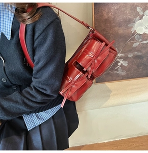 Retro burgundy PU leather shoulder bag with decorative bow-knot pockets worn by model