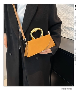 Detail of mustard yellow square bag with unique gold heart metal handle and fold design