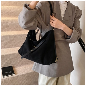 Detail of black suede hobo shoulder bag featuring adjustable strap and gold metal hardware