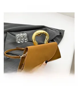 Detail of a chic square bag featuring a gold liquid metal handle and contrast texture