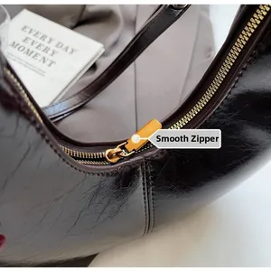 Macro shot of smooth gold metal zipper and shiny wrinkled leather on brown shoulder bag