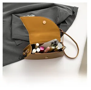 Internal view of brown flap crossbody bag showing capacity for phone and lipsticks