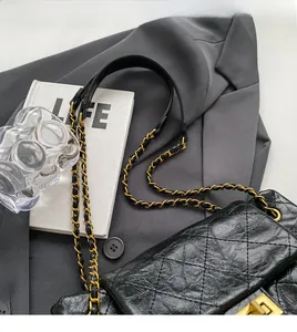 Detail of black quilted leather shoulder bag with gold-tone chain and elegant fold-over flap