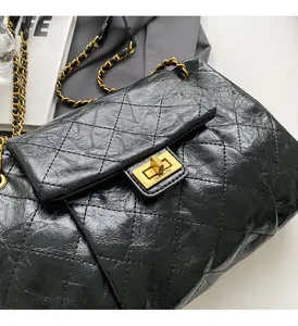 Close-up of black quilted leather texture and gold square twist lock on shoulder bag