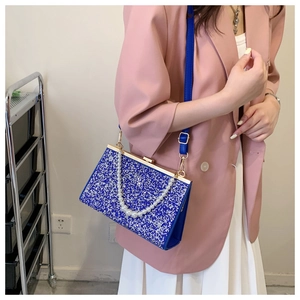 Detail of blue glitter evening clutch with pearl handle and gold metal frame closure