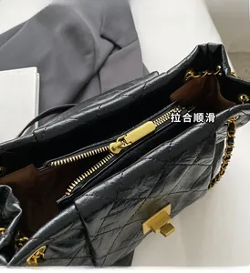 Close-up of golden metal zipper and quilted leather texture on a black shoulder bag