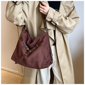 Detail of vintage burgundy suede tote bag with bronze metal buckle and leather straps