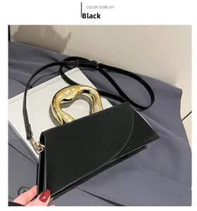 Detail of elegant black geometric handbag with a modern gold circular metal handle