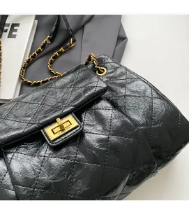 Detail of black quilted leather texture and golden metal twist lock on a chain bag