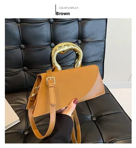 Detail view of brown leather handbag with unique gold abstract metal handle and strap