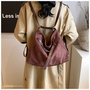 Close-up of brown suede shoulder bag with deep leather strap and golden metal buckle details