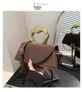 Detail of coffee brown trapezoid bag with artistic gold metal handle and matte leather