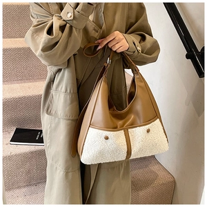 Detail view of the brown leather and white sherpa patchwork texture on a hobo tote bag