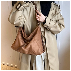 Detailed view of a vintage brown suede tote bag with leather straps and metal buckles
