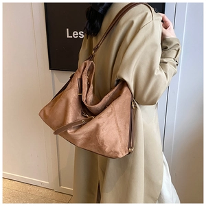Close-up of brown suede tote bag featuring adjustable leather strap and golden hardware
