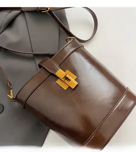 Gros plan détaillé du sac seau en cuir marron avec fermoir rotatif carré en métal doré