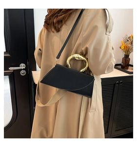 Chic black asymmetrical tote with sculptural gold handle styled with a beige trench coat