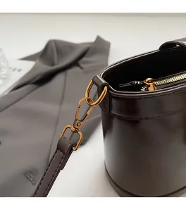 Gros plan détaillé des boucles dorées sur un sac seau en cuir marron foncé élégant