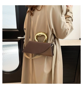 Detail of dark brown leather square bag with artistic horseshoe gold metal handle