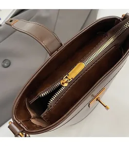 Détail de la fermeture éclair dorée lisse et du fermoir en métal sur le sac seau marron