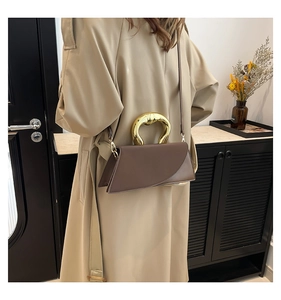 Detail of the elegant gold irregular metallic handle and brown leather flap bag texture