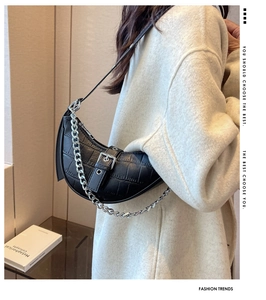 Detail of black faux crocodile leather underarm bag with silver chain strap and buckle