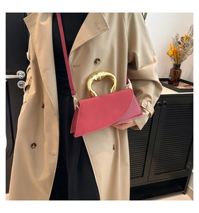 Detail of rose pink trapezoid handbag with a unique irregular gold metal handle