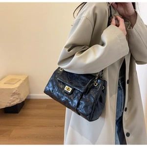Detail of classic black quilted leather bag with gold clasp and chain strap