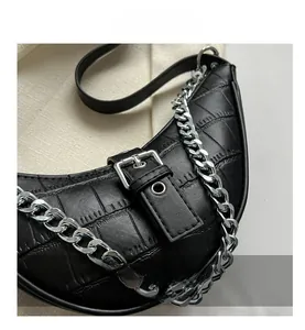 Detail of black faux leather dumpling bag with crocodile texture and silver chain strap
