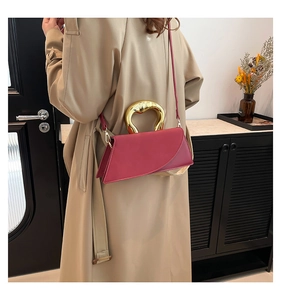 Detail of fuchsia square handbag with unique gold metal handle and asymmetrical design