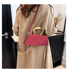 Model wearing a modern fuchsia asymmetrical crossbody bag with unique gold metal handle