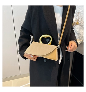 Detail of two-tone crossbody bag featuring a golden heart-shaped handle and leather strap