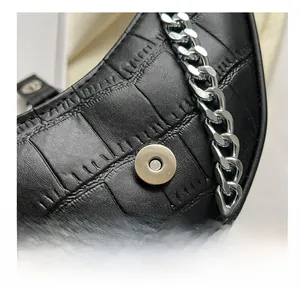 Detail of black crocodile texture handbag with magnetic clasp and silver chain