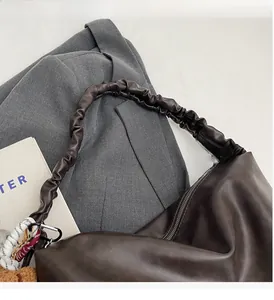 Detail of a dark brown leather bucket bag with a trendy scrunchie handle on a blazer