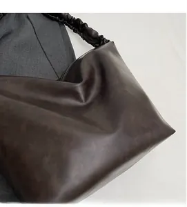 Detail of coffee brown tote bag with ruffled shoulder strap and smooth leather texture
