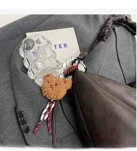 Close-up of pleated retro shoulder bag with plush bear charm and gathered handle texture