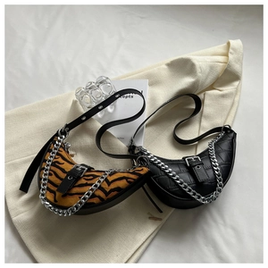Detail view of half-moon bags in tiger print knit and black crocodile texture with chains