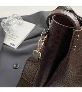 Detailed close-up of dark brown crocodile pattern leather with gold metal hardware buckle