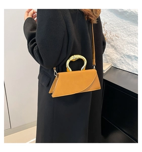 Detail of mustard yellow square bag with thick gold metal handle and diagonal flap