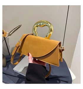 Close-up of ginger yellow crossbody bag featuring a unique gold irregular metal handle