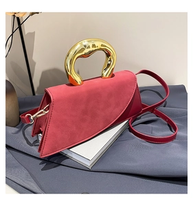 Detail of red square crossbody bag with artistic gold liquid metal handle and suede finish