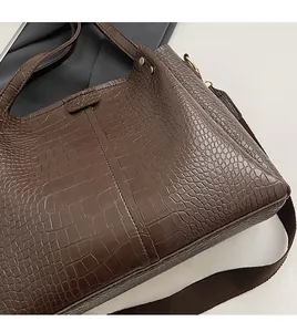 Close-up of deep brown crocodile embossed leather and woven shoulder strap on bucket bag