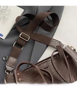 Detailed macro shot of dark brown crocodile texture leather and wide canvas shoulder strap