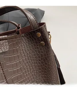 Detailed close-up of dark brown crocodile texture leather and gold metal rivet hardware