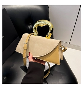 Detail of geometric patchwork handbag with gold metal handle and suede texture