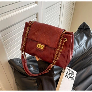 Detail of burgundy quilted leather bag with gold chain strap and twist-lock clasp