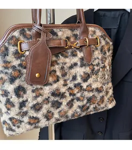 Détail du sac à main en peluche léopard avec lanières en cuir marron et boucles dorées