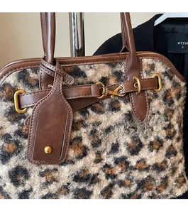 Détail d'un sac à main léopard en peluche avec finitions en cuir et boucles dorées