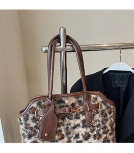 Détail d'un sac à main léopard en peluche avec finitions en cuir brun et boucle dorée
